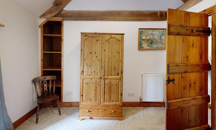 A twin bedroom with warm wood finishes and large sash window overlooking the countryside, blending rustic charm with comfort.